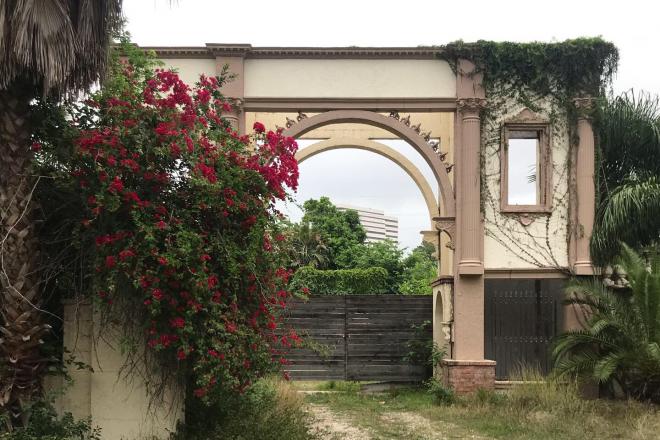 Overgrown arch with office building in background